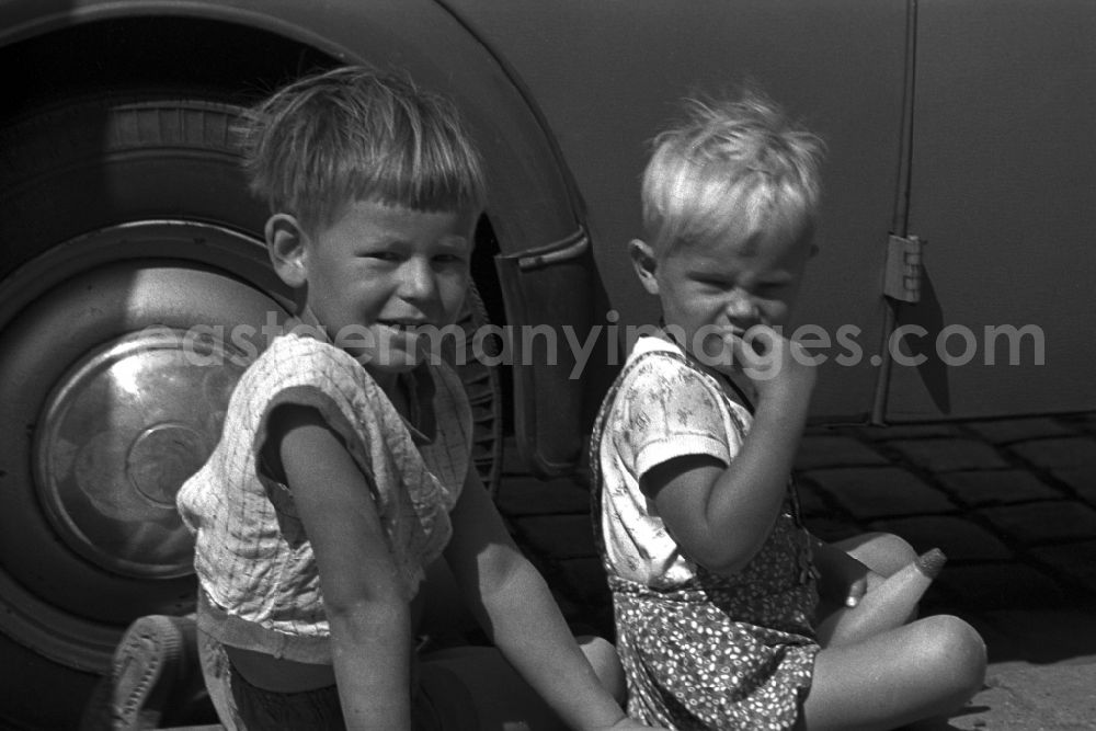 Magdeburg: Two little boys sitting on the sidewalk in front of a VW Beetle in Magdeburg in Saxony - Anhalt