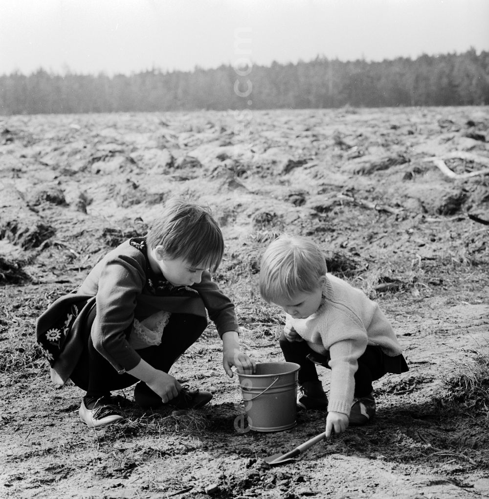 Wernigerode: Two small children with a bucket and a shovel play in the sand in Wernigerode in the federal state Saxony-Anhalt on the territory of the former GDR, German Democratic Republic