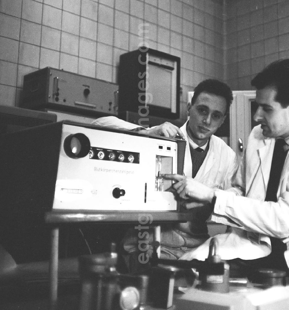 GDR picture archive: Ilmenau - Zwei Männer in Kitteln / ein Mann / Laborant präsentiert ein Blutkörperchenzähl-Gerät. Das Bild wurde in der Poli-Klinik in Ilmenau aufgenommen. Bestmögliche Qualität nach Vorlage!