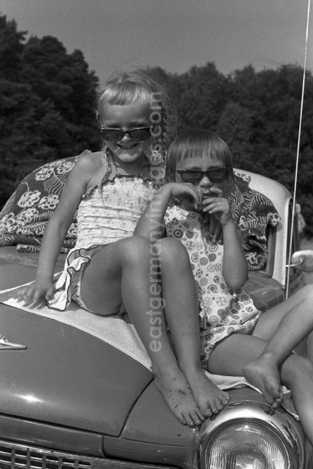 GDR image archive: Neuruppin OT Stendenitz - Two girls sitting barefoot on a hood of a Wartburg 311 in Brandenburg. Here on a family holiday at the campsite On Rottstielfließ on Tornowsee in Brandenburg