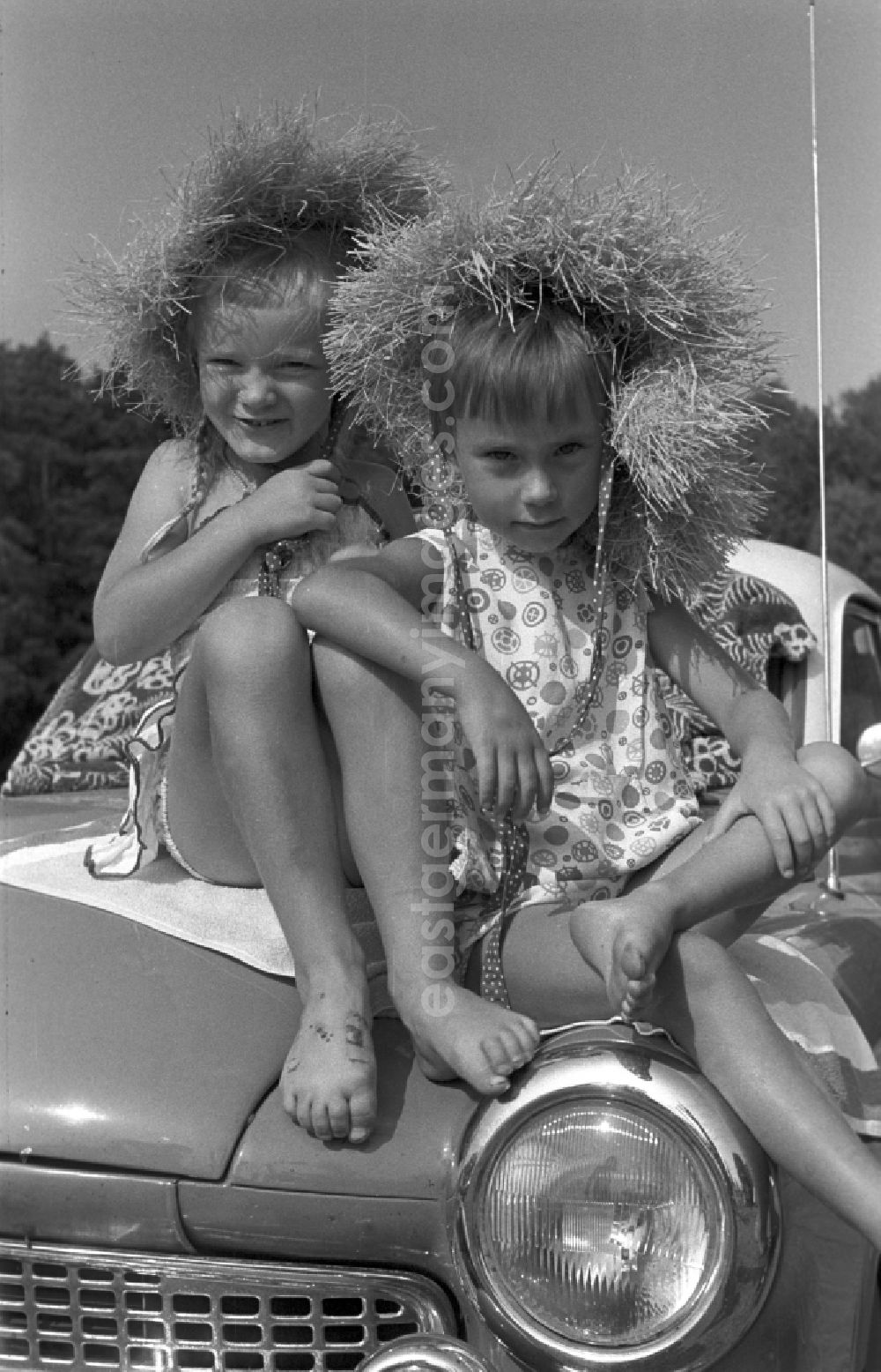 GDR photo archive: Neuruppin OT Stendenitz - Two girls sitting barefoot on a hood of a Wartburg 311 in Brandenburg. Here on a family holiday at the campsite On Rottstielfließ on Tornowsee in Brandenburg