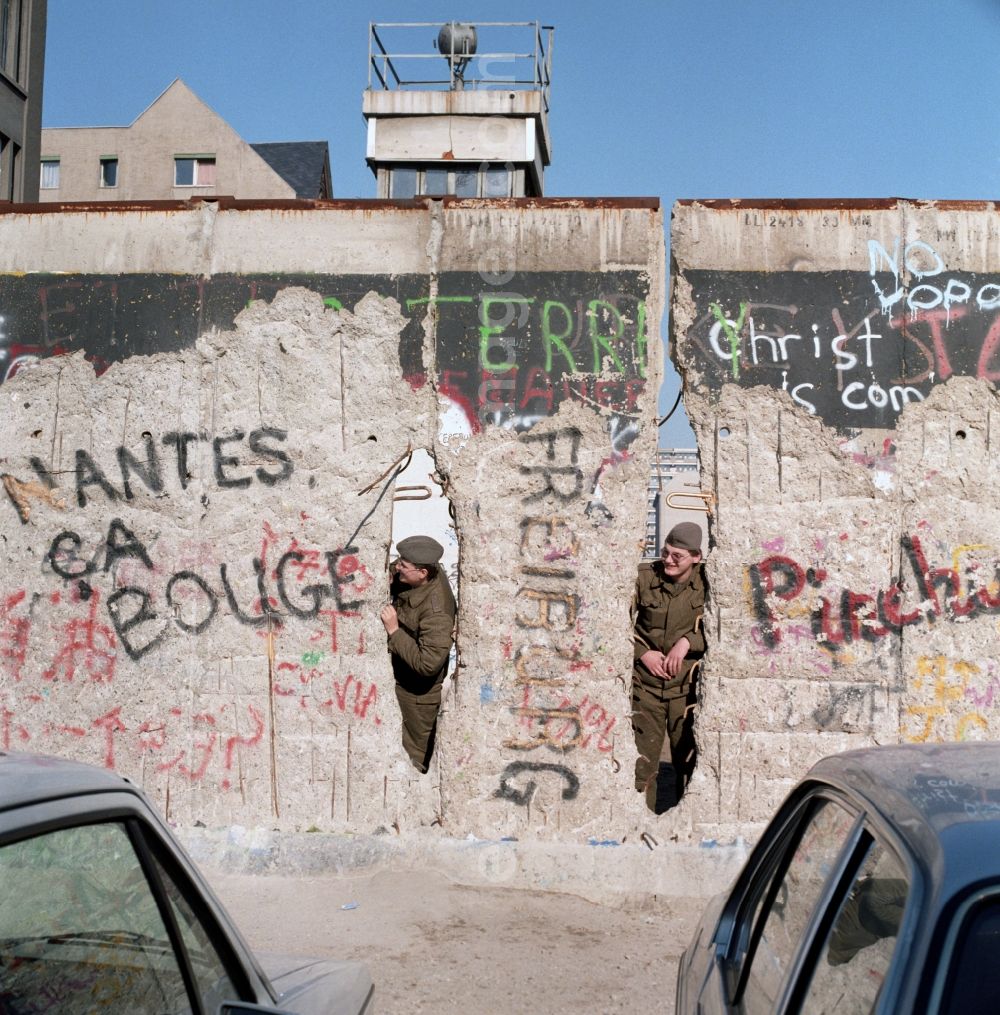 GDR image archive: Berlin - Two soldiers of the Border Troops of the GDR look through a hole in the Berlin Wall in Berlin