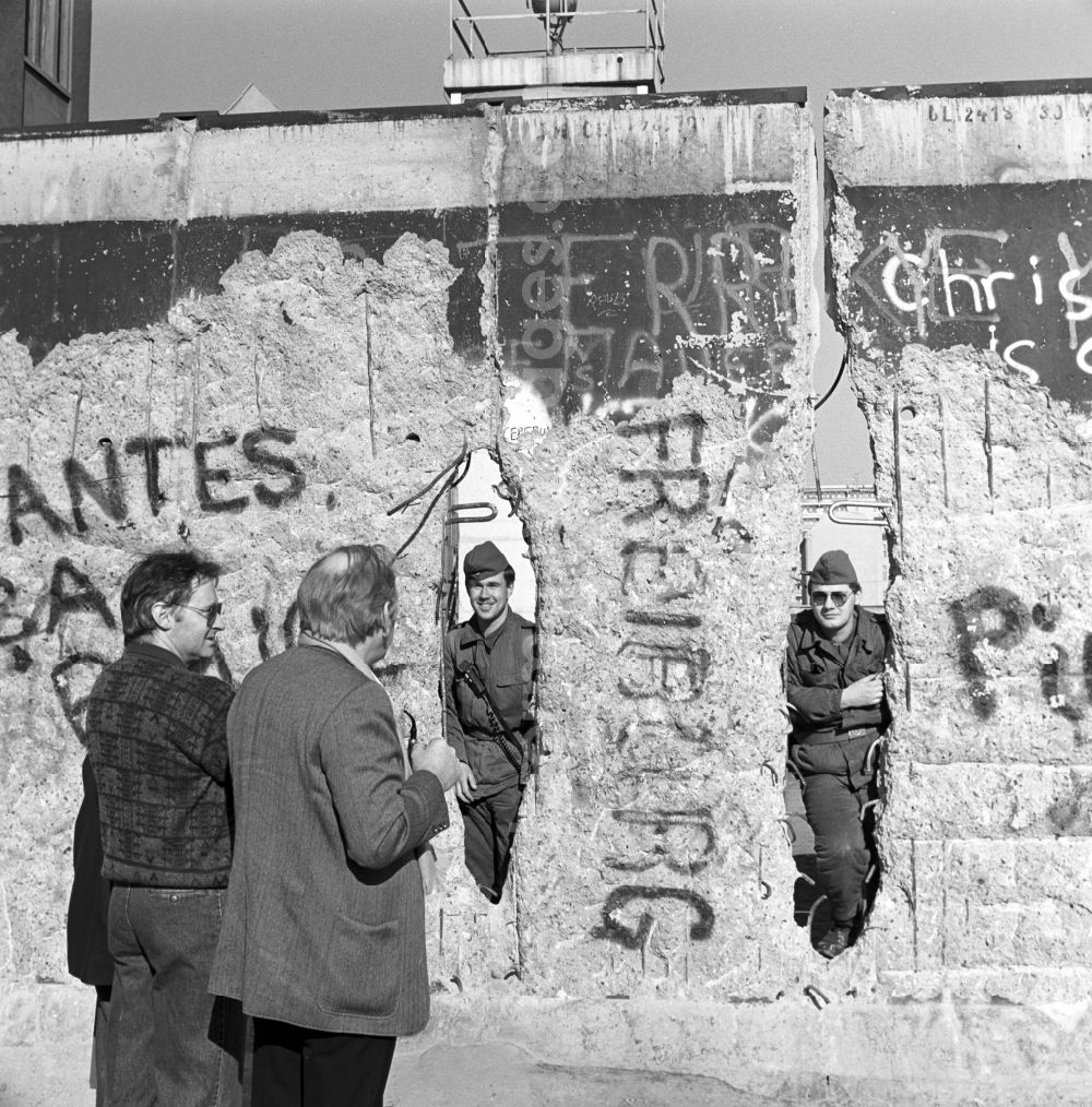 GDR photo archive: Berlin - Two soldiers of the Border Troops of the GDR look through a hole in the Berlin Wall in Berlin