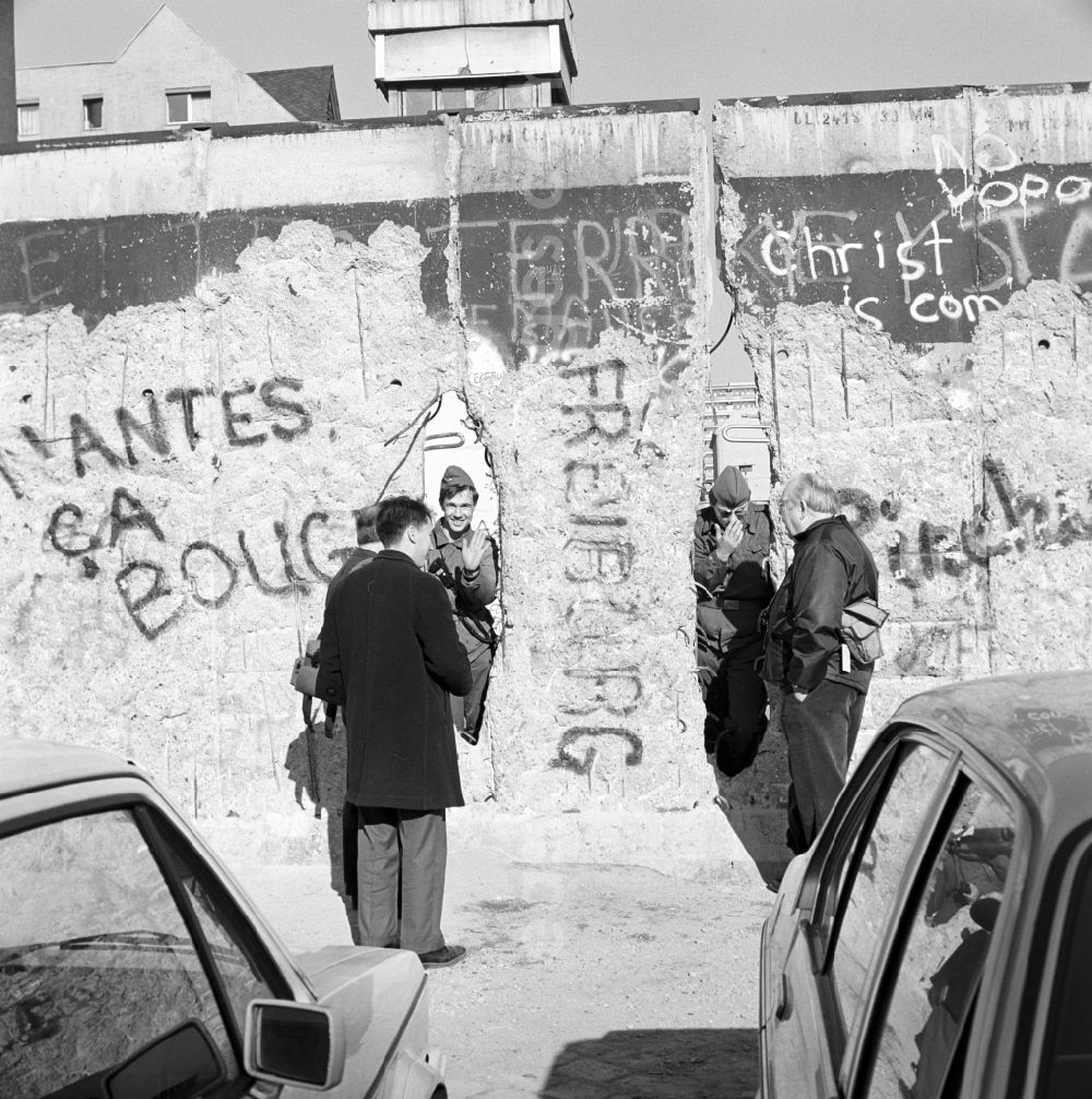 GDR image archive: Berlin - Two soldiers of the Border Troops of the GDR look through a hole in the Berlin Wall and talk to passers-by in Berlin