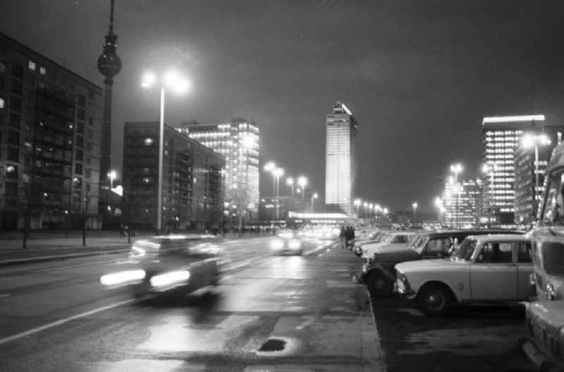 Nachtaufnahme: Blick auf die nächtliche Karl-Marx-Allee, Autos fahren auf Strasse, im Hintergrund das Hotel Stadt Berlin und der Berliner Fernsehturm. Autos stehen auf Parkplatz u.a. Moskwitsch.