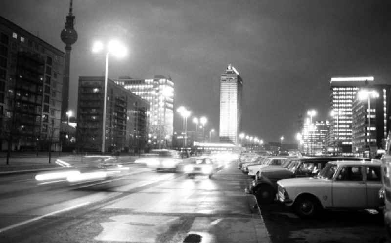 Nachtaufnahme: Blick auf die nächtliche Karl-Marx-Allee, Autos fahren auf Strasse, im Hintergrund das Hotel Stadt Berlin und der Berliner Fernsehturm. Autos stehen auf Parkplatz u.a. Moskwitsch.