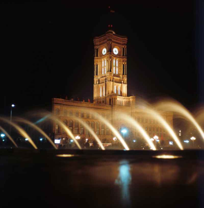 Nachtaufnahme: Blick durch Wasserfontänen auf das Rote Rathaus in Berlin-Mitte am Jahrestag der DDR. Mit der Errichtung des Fernsehturms sowie der Umgestaltung seiner Umgebung Mitte der 6