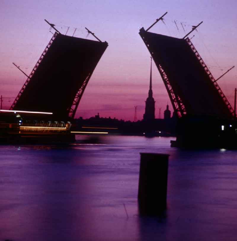 The castle bridge over the Bolshaya Neva at night in Saint Petersburg - Leningrad in Russia - Soviet Union - USSR. It connects Vasilievsky Island with the Admiralty island. The midfield is folded up at night to allow the passage of ships