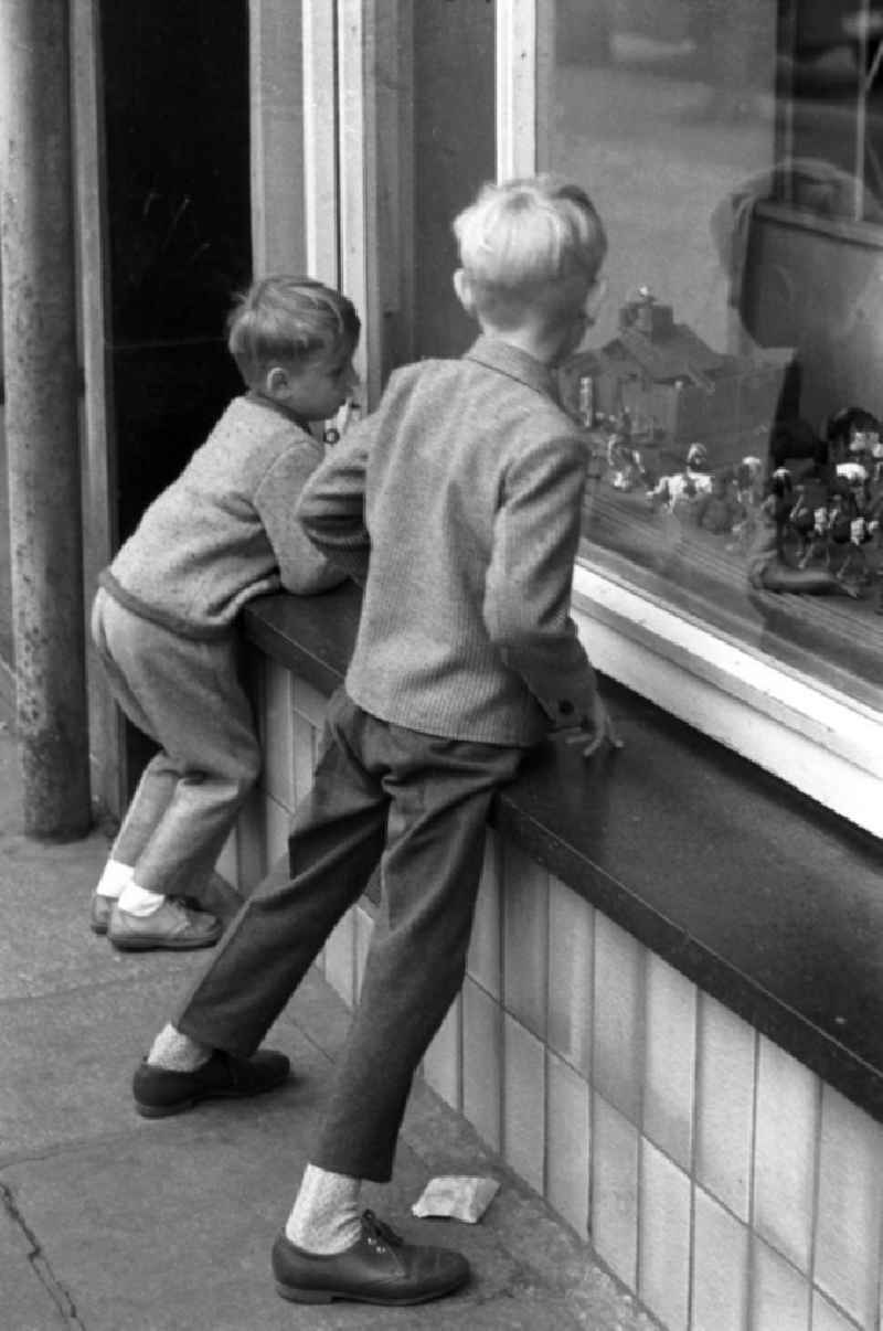 Zwei Jungs schauen neugierig durch das Schaufenster eines Dresdner Spielwarengeschäftes auf die ausgestellten Spielfiguren.