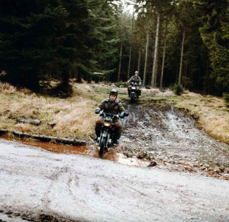 Border Patrol in snow in the winter with dog, car and motorcycle near Abbenrode in today's federal state of Saxony-Anhalt. The border guards are equipped with AK-47 machine guns