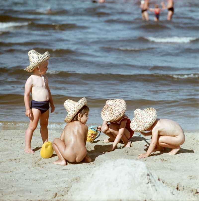 Kinder mit Strohhüten spielen am Ostseestrand bei Ahlbeck auf der Insel Usedom im Sand.