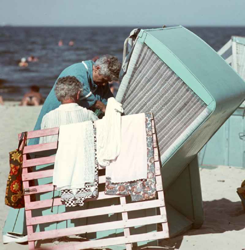 Im Schutz des Strandkorbes ziehen sich zwei Frauen am Ostseestrand bei Ahlbeck auf der Insel Usedom um.