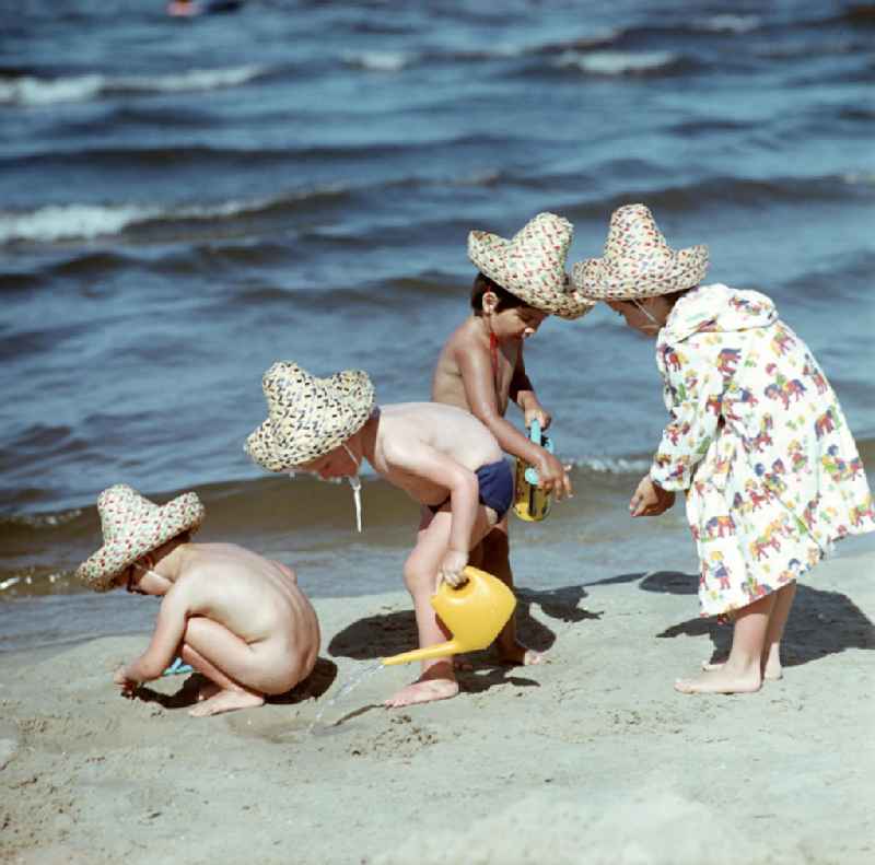 Kinder mit Strohhüten spielen am Ostseestrand bei Ahlbeck auf der Insel Usedom im Sand.