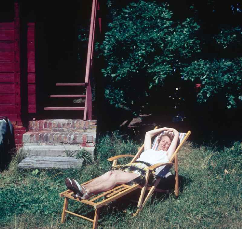 A woman lies in a deck chair and suns herself in Ahrenshoop in the federal state Mecklenburg-West Pomerania in the area of the former GDR, German democratic republic