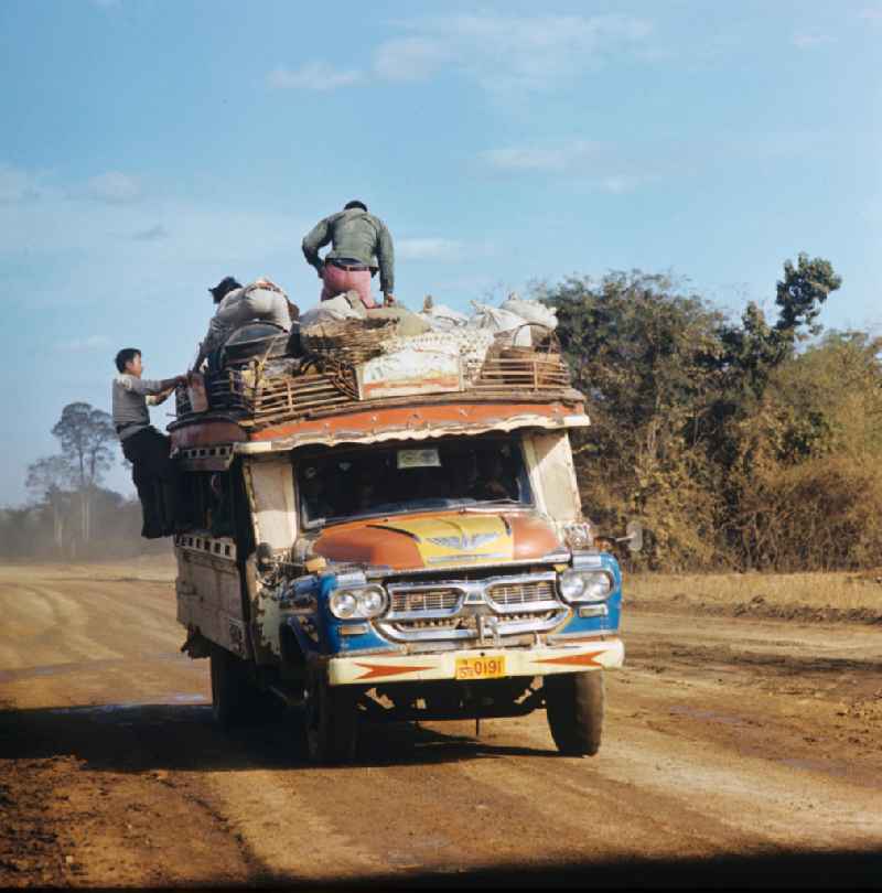 Mit Waren und Menschen vollbeladener Transporter auf einer Straße in der Demokratischen Volksrepublik Laos.