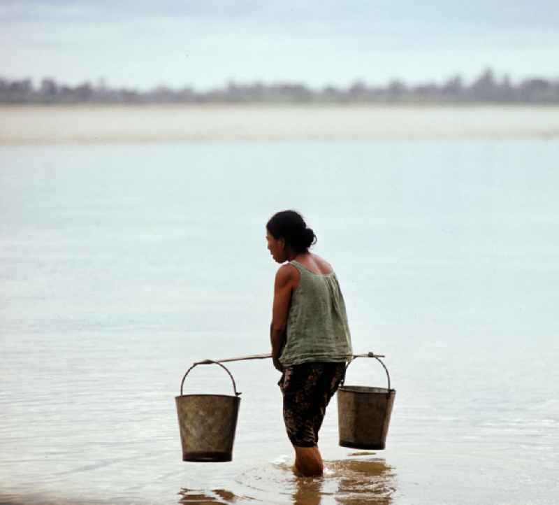 Frau holt mit Eimern Wasser im Fluß Mekong in der Demokratischen Volksrepublik Laos.