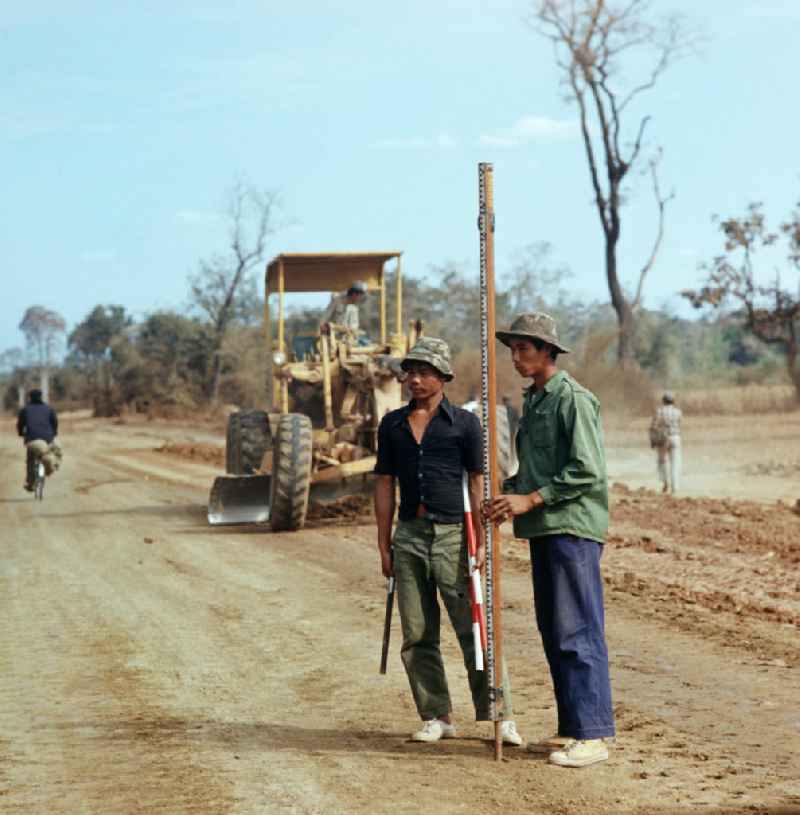 Arbeiter mit Vermessungsstange beim Straßenbau in der Demokratischen Volksrepublik Laos.