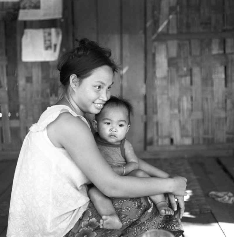 Mutter mit Kind in einer Hütte in der Demokratischen Volksrepublik Laos.