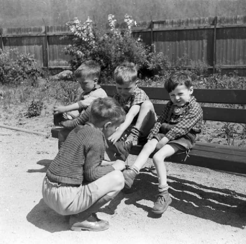 Boys in short leather trousers sit on a garden bench in Arnstadt in the federal state Thuringia in the area of the former GDR, German democratic republic