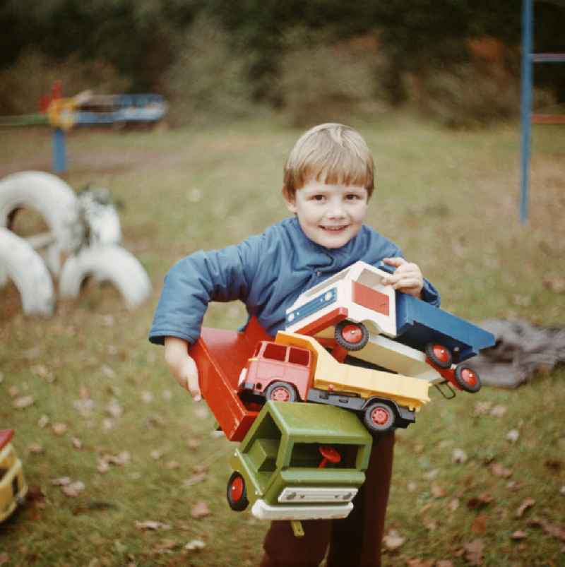 Im Kinderheim Bad Saarow trägt ein Junge Spielzeuglaster auf seinem Arm.