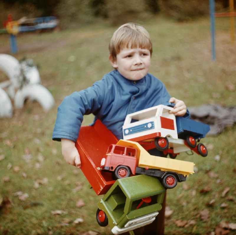 Im Kinderheim Bad Saarow trägt ein Junge Spielzeuglaster auf seinem Arm.