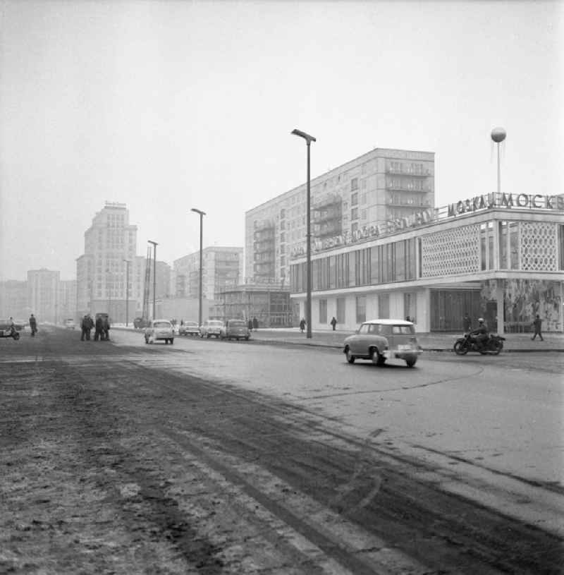 Blick über die Straße auf das Restaurant Moskau (heute bekannt als Café Moskau), Autos fahren auf Straße. Geplant durch die Architekten Josef Kaiser und Horst Bauer und von 1961 bis 1964 errichtet. Im Hintergrund im Bau befindlicher letzter Bauabschnitt. Adresse: Karl-Marx-Allee 34, 1