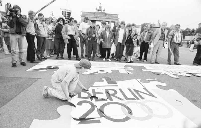 Olympiafest am Brandenburger Tor. Junge / Kind setzt Puzzel auf Boden zusammen, Passenten / Menschen drumherum schauen zu.