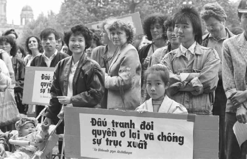 Vietnamese guest workers - contract workers on Karl-Liebknecht-Strasse in front of the palace hotel with protest poster and banner slogan 'Right to stay for GDR contract workers' in the Mitte district of Berlin East Berlin on the territory of the former GDR, German Democratic Republic