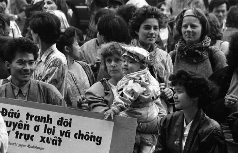 Vietnamese guest workers - contract workers on Karl-Liebknecht-Strasse in front of the palace hotel with protest poster and banner slogan 'Right to stay for GDR contract workers' in the Mitte district of Berlin East Berlin on the territory of the former GDR, German Democratic Republic
