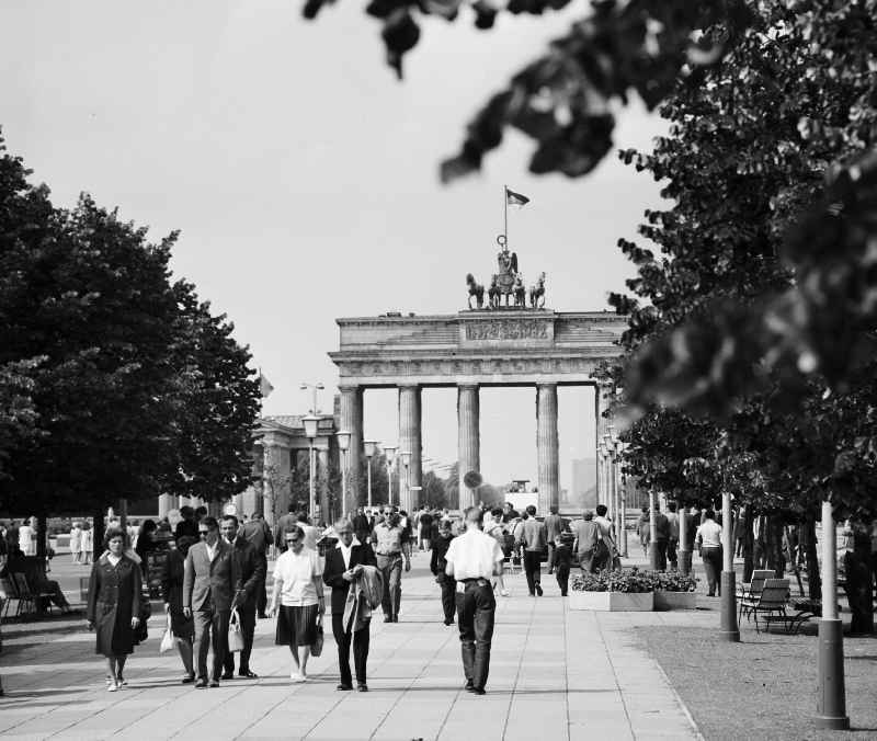 Menschen flanieren rund um das Brandenburger Tor auf der Strasse Unter den Linden in Berlin-Mitte.