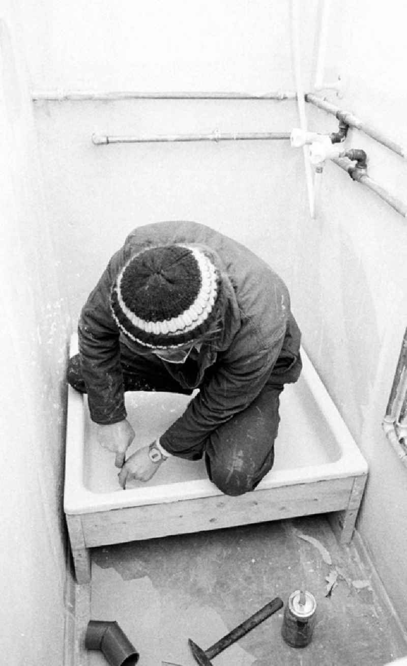 Ein Arbeiter setzt in einem Altbau-Wohnhaus in der Britzer Straße in Niederschöneweide eine neue Duschtasse in ein Badezimmer.