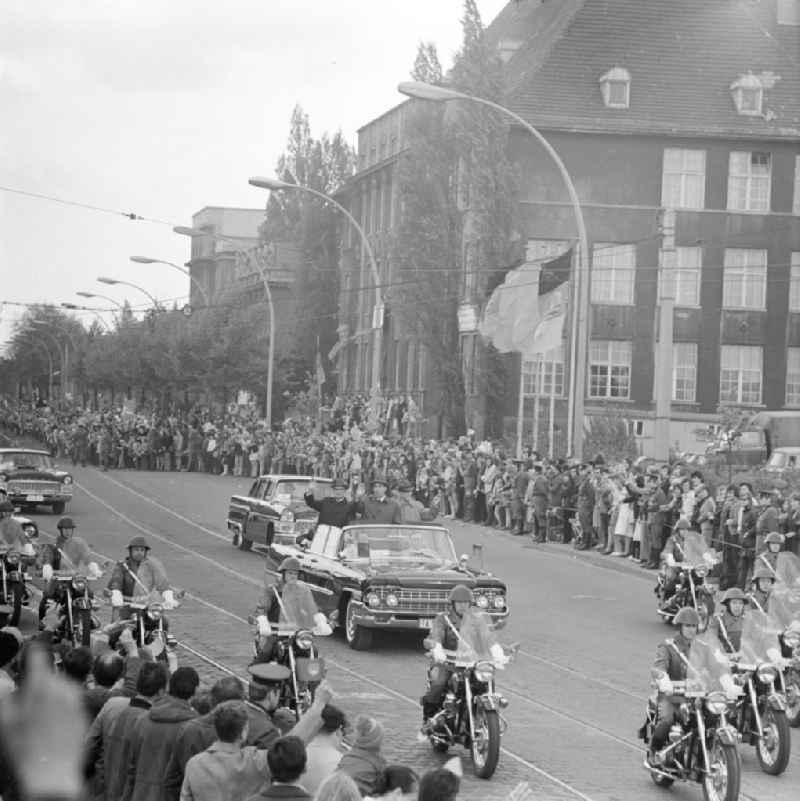 Erich Honecker und Besuch aus der Sowjetunion Herr Breschnew winkend im fahrenden Auto, Zuschauer stehen am Straßenrand.