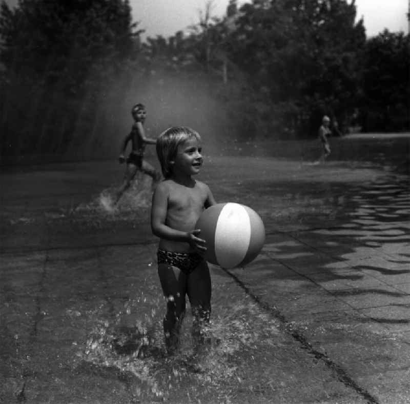 Planschbecken / Kinderbad in der Singerstrasse. Ein Kind spielt mit seinem Ball / Wasserball im Wasser.