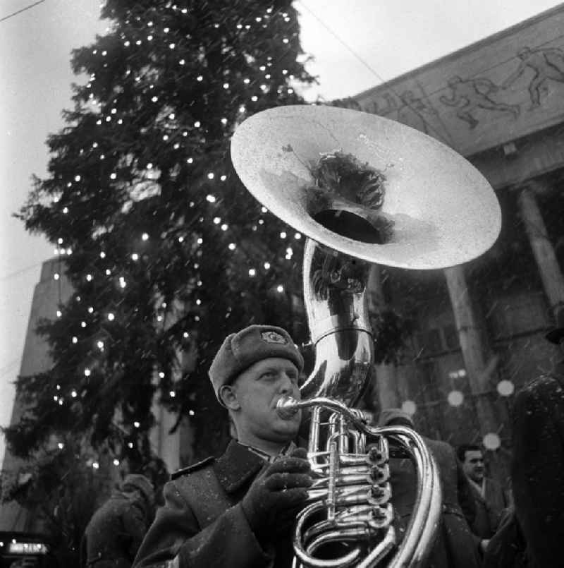 Ein uniformierter Musikant einer Blaskapelle der bewaffneten Organe der DDR vor der Sporthalle am Strausberger Platz spielt während der Eröffnung des Weihnachtsmarktes auf seinem Sousaphon bzw. Sousafon (eine Form der Tuba).