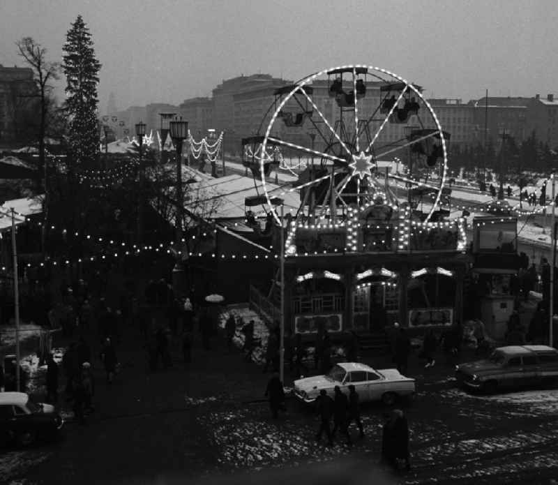 Blick von oben auf den Weihnachtsmarkt am Strausberger Platz mit Riesenrad, ein mit Lampen geschmückter Weihnachtsbaum und an der Karl-Marx-Allee aufgestellte Buden.