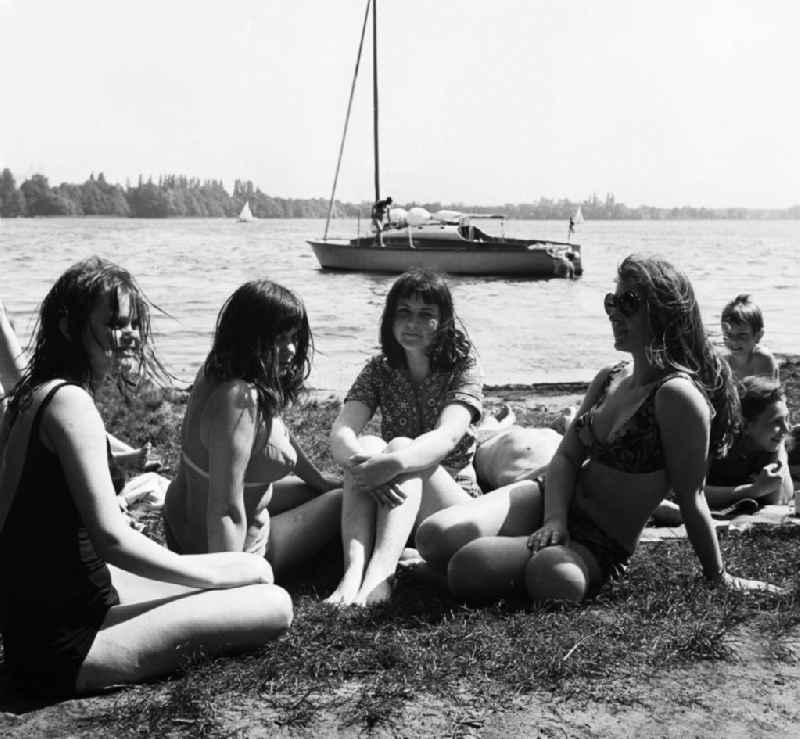 Jugendliche / Junge Frauen an der Badestelle auf dem Internationalen Campingplatz (Intercamping) bei Schmöckwitz in Berlin-Köpenick am Ufer des Krossinsee. Ein Segelboot ist im Hintergrund auf dem See.