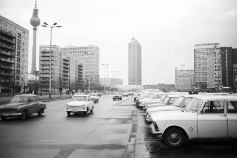 Blick auf die Karl-Marx-Allee, Autos fahren auf Strasse (u.a. Trabant), im Hintergrund das Hotel Stadt Berlin und der Berliner Fernsehturm. Autos stehen auf Parkplatz u.a. Moskwitsch.