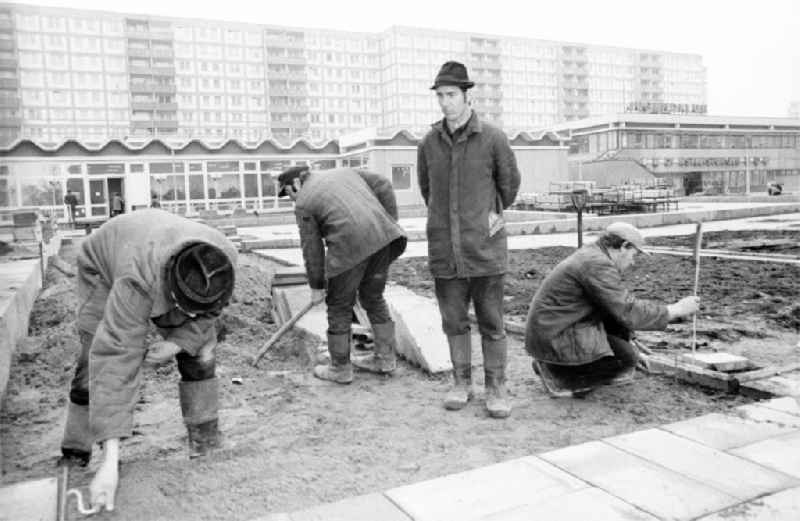 Paving work and laying pavement slabs in the green areas in front of the facades of an industrially manufactured prefabricated large housing estate on Weissenseer Weg (formerly Ho-Chi-Minh-Strasse) in the district of Lichtenberg in Berlin East Berlin in the area of ​​the former GDR, German Democratic Republic