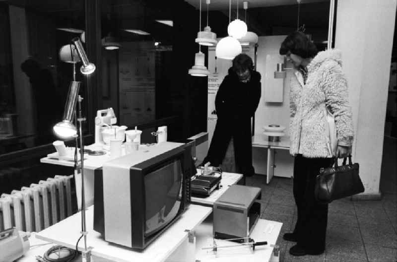Zwei Frauen besuchen die Bauausstellung im Ausstellungszentrum am Fuße des Berliner Fernsehturm und betrachten aufmerksam verschiedene elektronische Geräte wie z.B. einen Fernseher.