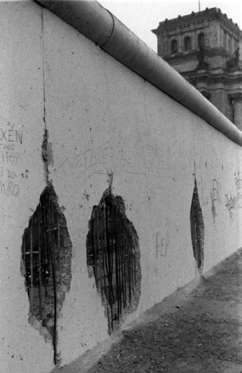Blick über die bereits löschrige Mauer auf den Berliner Reichstag. Als Erinnerung wurden gern Stücke der Mauer mitgenommen, so entstanden die Löscher, sie hießen auch Mauerspechte.