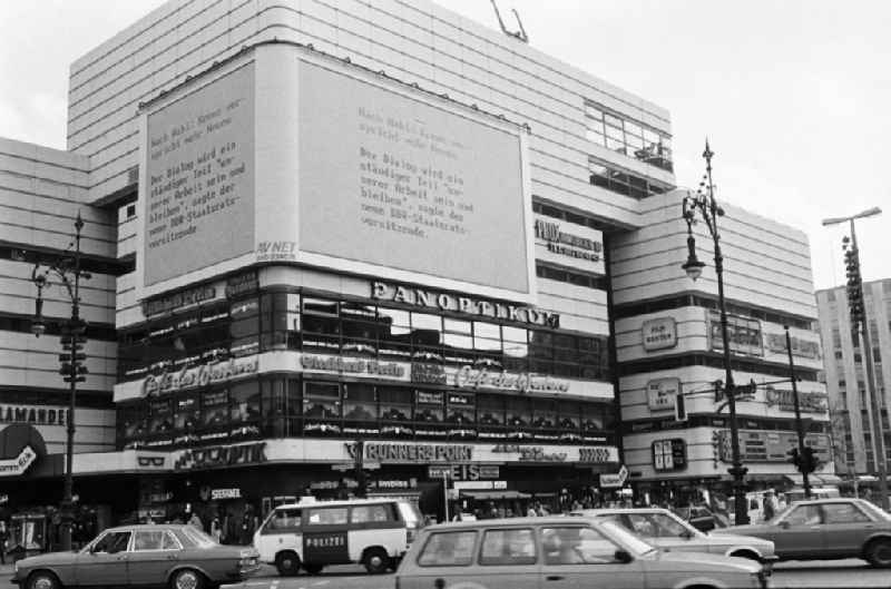 Blick über die dicht befahrene Einkaufsstraße Kurfürstendamm in West-Berlin. Über eine Videowand werden die Bürger über die Entwicklungen in der DDR informiert.