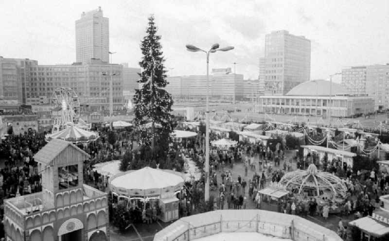 Blick auf den Weihnachtsmarkt am Alexanderplatz in Berlin-Mitte. Besonders beliebt sind die zahlreichen Fahrgeschäfte. Im Zentrum des Weihnachtsmarktes steht die traditionelle Weihnachtsfichte. Im Hintergrund sind das Alexanderhaus (l), das Hochhaus-Hotel 'Stadt Berlin' (dahinter), die Kongresshalle (r) und das 'Haus des Lehrers' (links daneben) zu sehen.