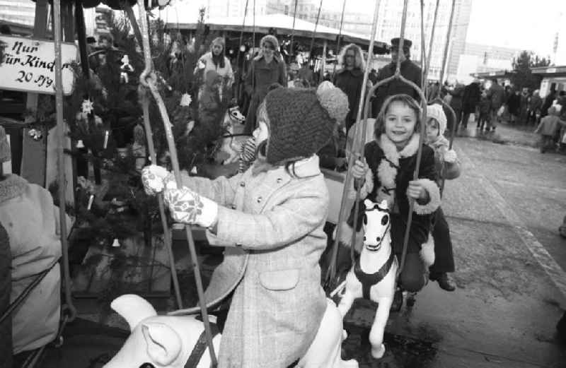 Kinder bei einer Fahrt mit dem Karussell auf dem Weihnachtsmarkt am Alexanderplatz in Berlin-Mitte. Eine Fahrt kostet 2