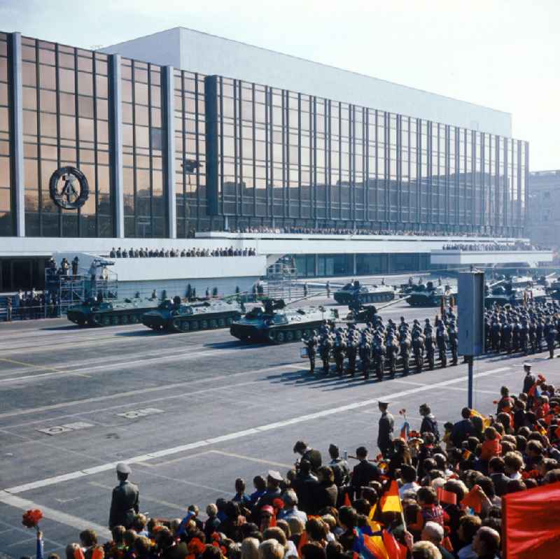Parade der NVA auf dem Schloßplatz zum 28. Jahrestag der DDR. Soldaten und Panzer vor dem PdR. Zuschauer mit Winkelementen im Vordergrund. Im Hintergrund der Palast der Republik mit Tribünen. Symbol / Emblem der DDR an der GlasFassade des PdR.