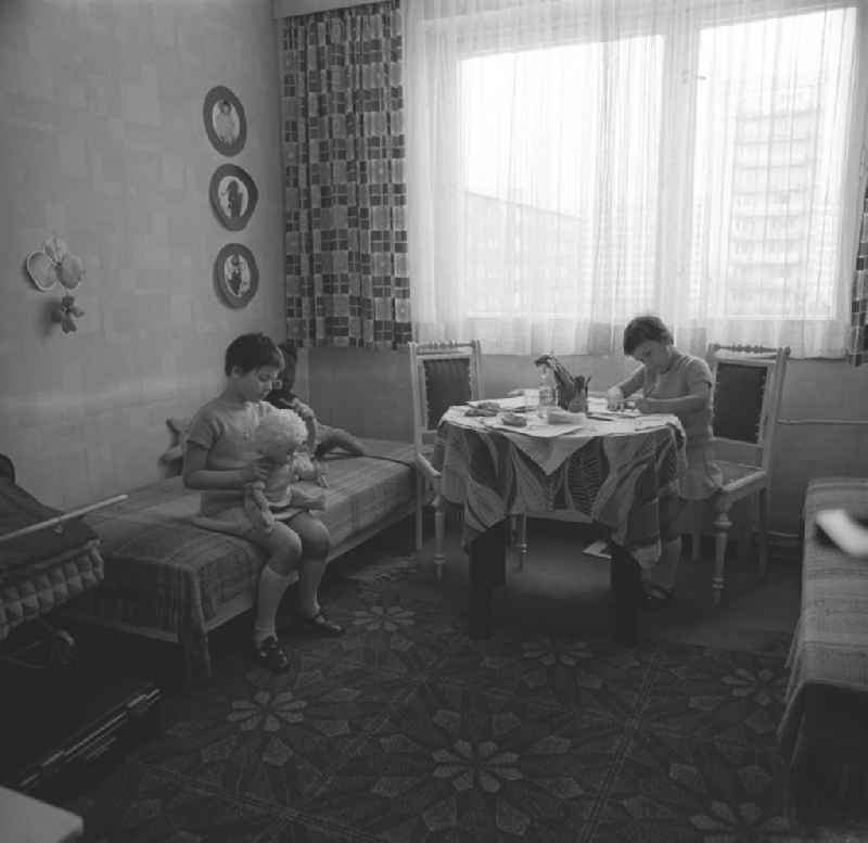 Zwei Tage im Leben einer alleinerziehenden Frau mit zwei Kindern in Ostberlin. Zwischen Privatem, Arbeit und Weiterbildung ( EDV Kurs ). Töchter im Kinderzimmer. Ein Mädchen spielt mit einer Puppe, die andere sitzt am Tisch und malt.