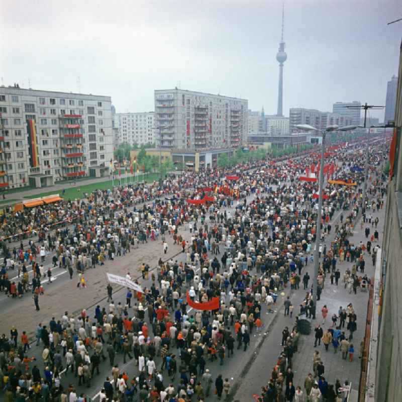 Tausende Menschen mit Transparenten und Plakaten laufen zur traditionellen Demonstration in der Hauptstadt der DDR am 1. Mai 1975, dem 'Internationalen Kampf- und Feiertag der Werktätigen für Frieden und Sozialismus', auf der Berliner Karl-Marx-Allee in Richtung Alexanderplatz.