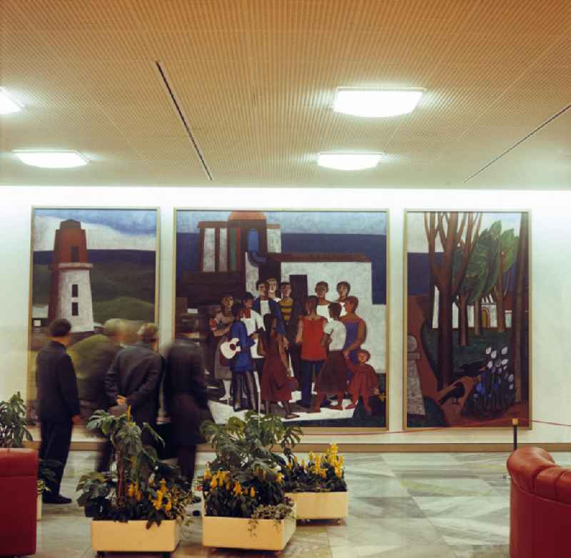 Kurz nach seiner Eröffnung am 23. April 1976 besichtigt eine Besuchergruppe im Palast der Republik (PdR) in Berlin das dreiteilige Gemälde 'Die schaffenden Kräfte' von Kurt Robbel. In den Foyers des Kulturpalastes hingen mehrere großformatige Gemälde von 16 prominenten Künstlern und Malern der DDR, viele im Stil des Sozialistischen Realismus.