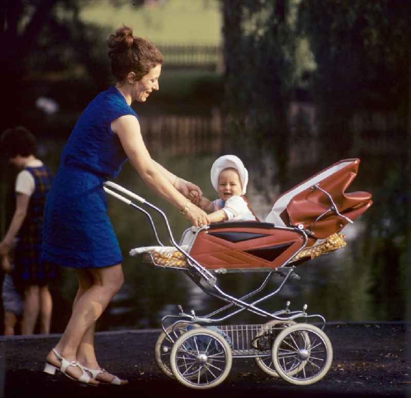 Eine Mutti mit Baby im Kinderwagen genießt im Volkspark Friedrichshain in Berlin ihr junges Familienglück.