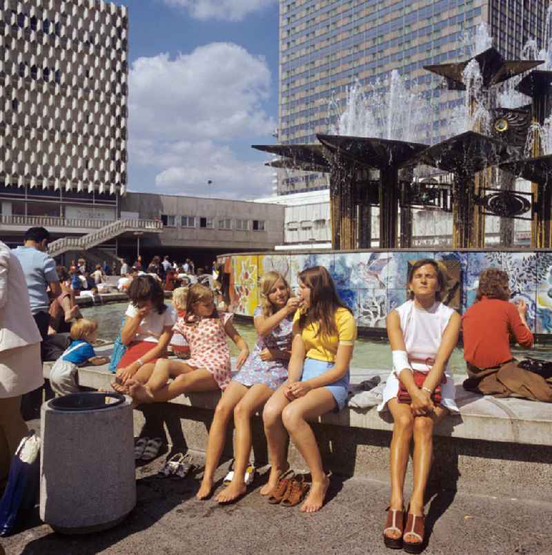 Touristen und Einheimische genießen die sommerlichen Temperaturen am Brunnen der Völkerfreundschaft, umgangssprachlich Nuttenbrosche, auf dem Berliner Alexanderplatz. Der 197