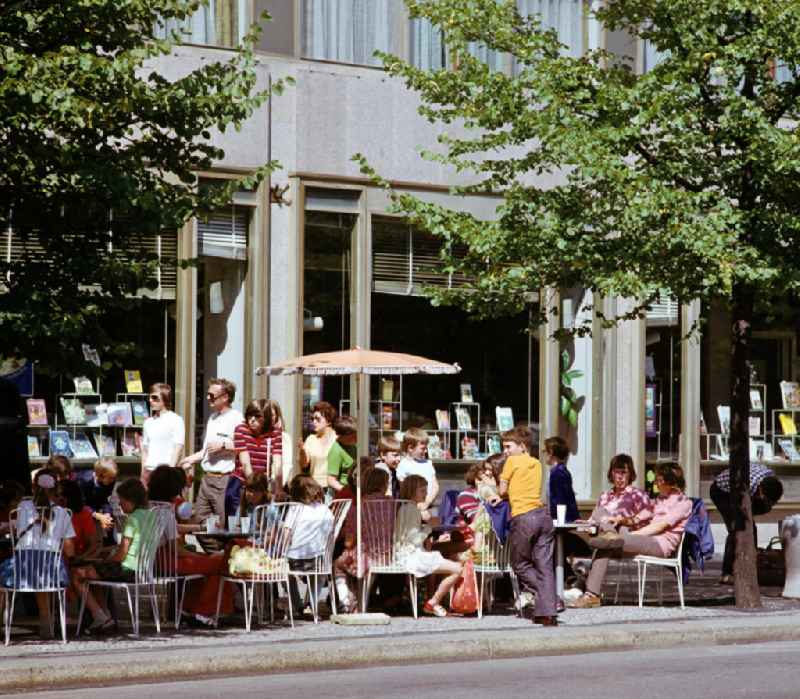 Eine Kindergruppe sitzt in einem Café Unter den Linden in Berlin-Mitte, im Hintergrund die Auslagen einer Buchhandlung.